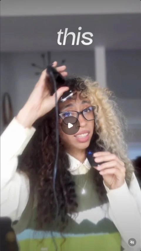 A creator holding clippers beside her hair to demonstrate a surprising opening.